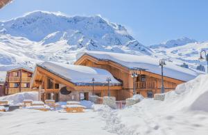 a ski lodge with snow covered mountains in the background at Les Balcons Platinium Val Thorens in Val Thorens