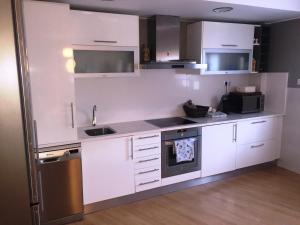 a kitchen with white cabinets and a sink and a dishwasher at Apartamentos Mequedo in Alcañiz
