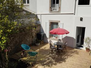 a patio with a table and chairs and a red umbrella at Les Appartements du 31 - Centre Ville - 2è étage - 50 m2 in Quimper