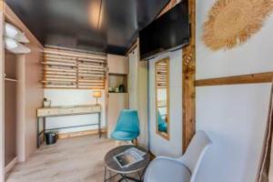 a living room with a blue chair and a train at Hôtel Le Grain de Sable in Arès