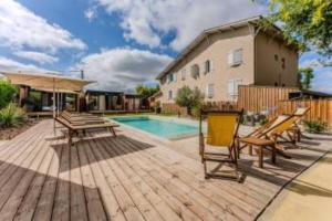 a patio with a table and chairs and a pool at Hôtel Le Grain de Sable in Arès