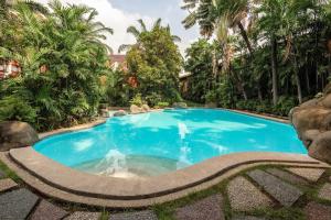 a swimming pool in a resort with palm trees at Condotel in Pasig City - Hampton Gardens in Manila
