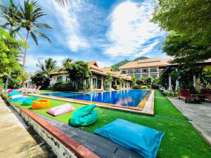 a resort swimming pool with colorful inflatables on the grass at Poolsawat Villa - SHA Plus in Lamai