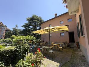 a patio with tables and chairs and a yellow umbrella at Cernobbio Residence in Cernobbio