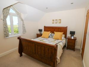 1 dormitorio con cama de madera y ventana en Llain Gwynfor, en Haverfordwest
