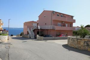 a pink building with cars parked in front of it at Surf & joy - Croatia vacation rentals seaview apartment in Okrug Gornji
