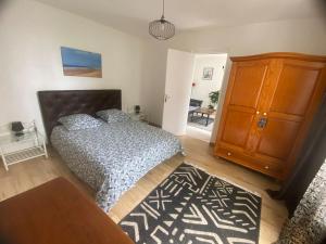 Un dormitorio con una cama y un armario de madera. en Votre Petite Maison, en Bagneux