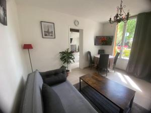 una sala de estar con un sofá y una mesa en Votre Petite Maison, en Bagneux