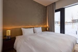 a bedroom with a large white bed with a window at Shiyuki in Furano