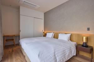 a bedroom with a large bed with white sheets at Shiyuki in Furano +19 photos