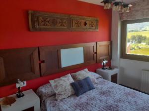 ein Schlafzimmer mit einem Bett und einer roten Wand in der Unterkunft Apartamentos Ría de Villaviciosa in Villaviciosa