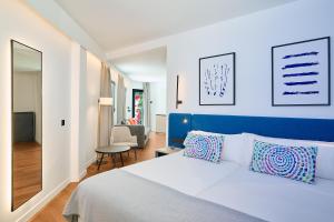 a bedroom with a white bed and a blue headboard at Apartamentos Luna Suites Granada in Granada +27 photos