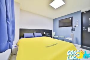 a bedroom with a large yellow bed with blue walls at Ekonomy Hotel Nampo in Busan