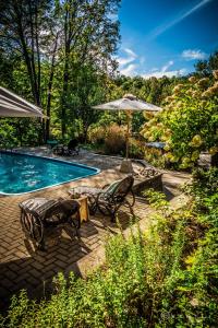 a swimming pool with two chairs and an umbrella at Villa Nao in Roxton Falls