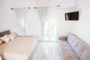 a white living room with a couch and a tv at Villa Theano 2 in Toroni