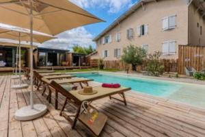 a pool with tables and an umbrella next to a building at Hôtel Le Grain de Sable in Arès