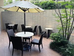 a patio with tables and chairs and an umbrella at Dormy Inn Premium Shibuya-jingumae in Tokyo