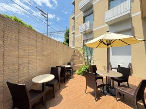 a patio with tables and chairs and an umbrella at Dormy Inn Premium Shibuya-jingumae in Tokyo