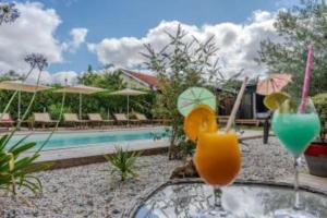 two drinks on a table next to a swimming pool at Hôtel Le Grain de Sable in Arès