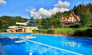 a large swimming pool in front of a large house at Hotel Sluníčko in Ostravice