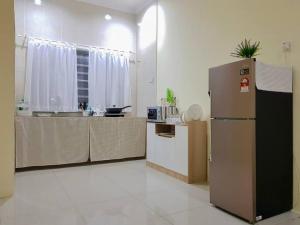 a kitchen with a refrigerator in the middle of a room at Lovely Homestay in Gerik with Free Netflix & WiFi in Gerik
