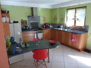 a kitchen with wooden cabinets and a table with red chairs at chez Marie et Eric in Dieffenbach-au-Val