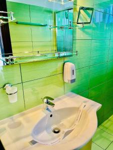 a bathroom with a sink and a green wall at Pensiunea Roua - Mountain View in Sinaia