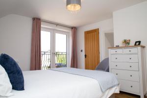 Un dormitorio con una cama blanca y una ventana. en Derwen House Newport, Pembrokeshire, en Newport