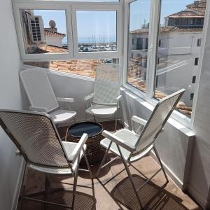 a row of chairs sitting on a balcony with windows at Duquesa Harbour Club Aparthotel in Manilva