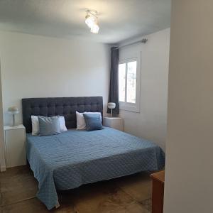a bedroom with a bed with a blue comforter and a window at Duquesa Harbour Club Aparthotel in Manilva