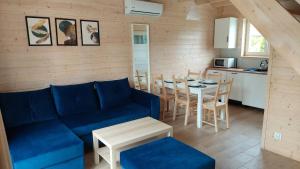 a living room with a blue couch and a table at Domki letniskowe Wega - basen ogrodowy plac zabaw parking grill wifi in Sianozety