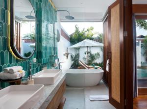 a bathroom with two sinks and a tub at The Arca Villas by GenuineHost in Sanur