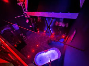 Loveroom de luxe - Thème 50 nuances de grey maison privative spa insolite في Douchy-les-Mines: حمام مع حوض أبيض وأضواء حمراء +8 صور