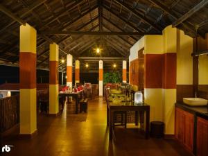 a restaurant with tables and chairs in a room at Wayanad Kuruva Isles Jungle Resort in Chekadi