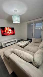 Una sala de estar con un sofá y un televisor. en Black Room: Votre Love Room près de Lyon, en Vénissieux