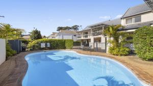 a swimming pool in front of a house at Azure - Luxe, Pool Beachfront in Kororo Basin