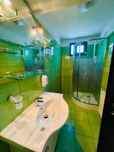 a green bathroom with a sink and a shower at Pensiunea Roua in Sinaia