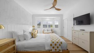 a white bedroom with a bed and a ceiling fan at Ellie's Holiday Escape - Pool, Romantic, Fireplace in Coffs Harbour