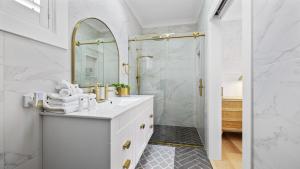 a white bathroom with a shower and a sink at Ellie's Holiday Escape - Pool, Romantic, Fireplace in Coffs Harbour