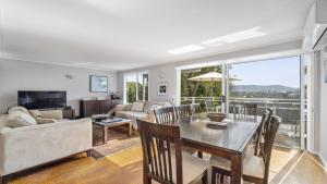 a living room with a table and a couch at Jetty Hideaway - Cosy Cottage, Fireplace, Gardens in Coffs Harbour