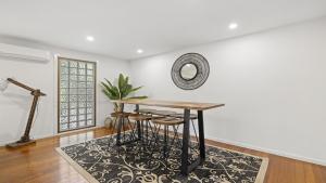 a dining room with a table and stools at Kasuari - Just Steps to Pool and Beach in Coffs Harbour