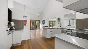 a large kitchen with white appliances and wooden floors at Kasuari - Just Steps to Pool and Beach in Coffs Harbour