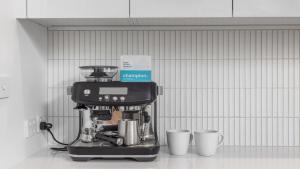 a coffee machine with two cups on a counter at Luxe Jetty Apartment - Stylish, Walk to Beach & Cafes in Coffs Harbour