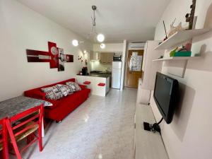 a living room with a red couch and a kitchen at LE DUNE Casa vacanze Salento Puglia in Torre dell'Orso