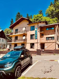a suv parked in a parking lot in front of a building at Pensiunea Roua in Sinaia