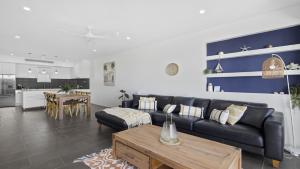 Una sala de estar con un sofá negro y una mesa. en Pacific Piers - Walk to Cafes, Pub & Jetty Beach, en Coffs Harbour