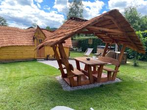 a wooden pergola with a table and chairs in a yard at Cabane Insolite Cosy in Ramonchamp