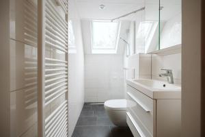a white bathroom with a toilet and a sink at Jonkerstee 59 - Ouddorp in Ouddorp +28 photos