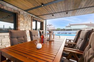 una mesa de madera y sillas en un patio con piscina en Beautiful Villa Baraka with pool near Pazin, en Kanfanar