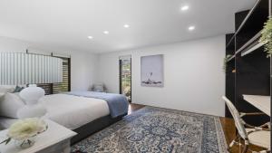 a bedroom with a bed and a table with a vase on it at Victoria's - Hamptons Beachside Residence in Emerald Beach